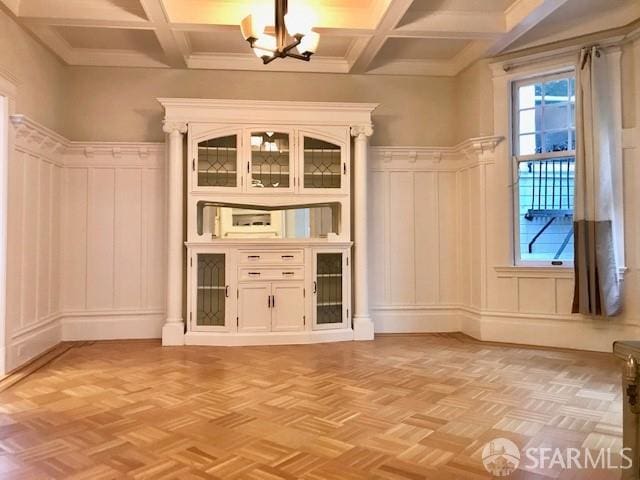 unfurnished room with a decorative wall, a chandelier, coffered ceiling, and beamed ceiling