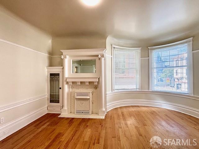 unfurnished living room with wood finished floors and a fireplace with flush hearth