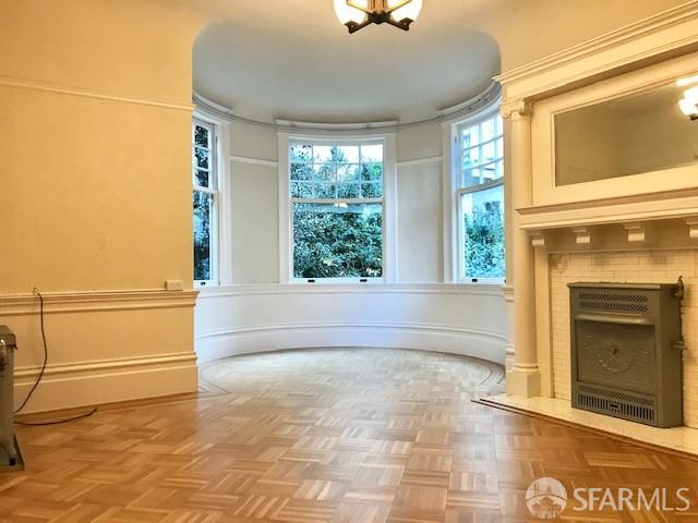 unfurnished living room featuring a decorative wall, a fireplace with flush hearth, and a chandelier