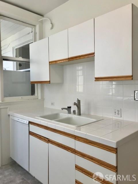 kitchen with white cabinets, white dishwasher, and tasteful backsplash