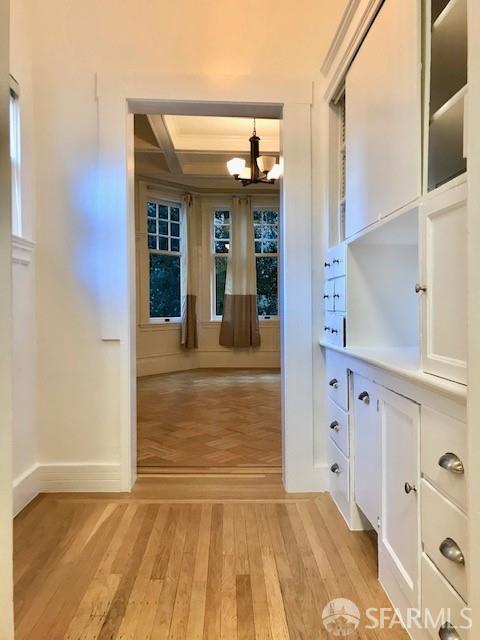 corridor featuring a chandelier, light wood-style floors, and coffered ceiling