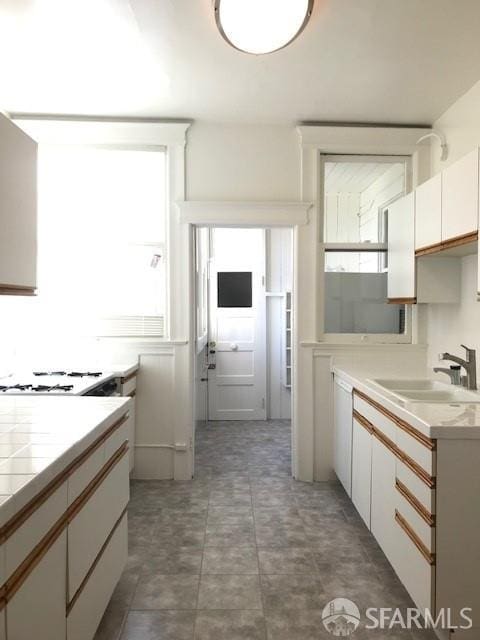kitchen featuring light countertops, white cabinets, and white gas cooktop