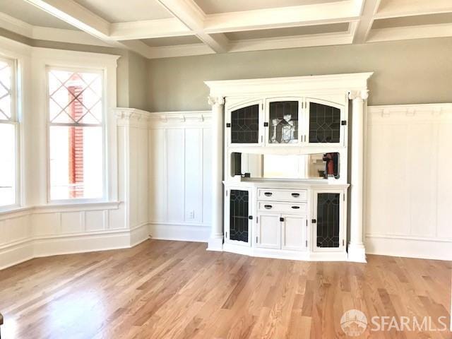 bar featuring coffered ceiling, beamed ceiling, a decorative wall, light wood finished floors, and a wainscoted wall