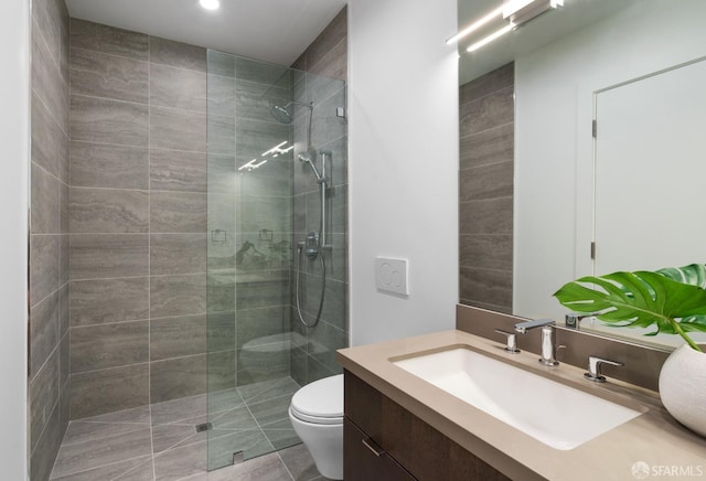 bathroom with a tile shower, tile patterned floors, vanity, and toilet