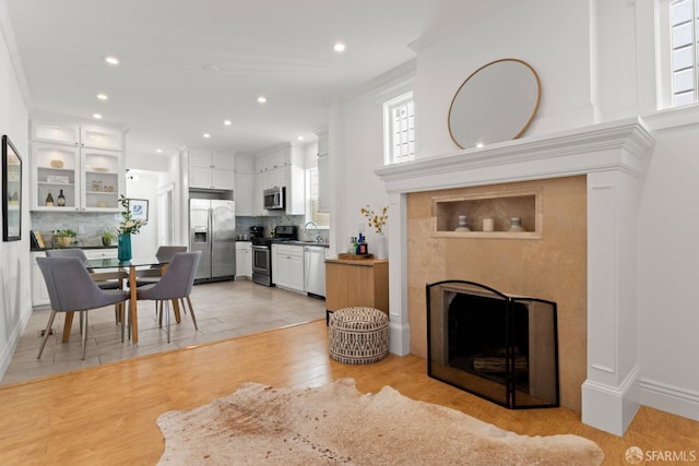 living room with ornamental molding, sink, a wealth of natural light, and light hardwood / wood-style flooring