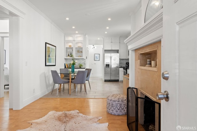 dining room featuring built in shelves, light wood-type flooring, and ornamental molding