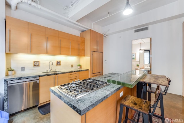 kitchen with tasteful backsplash, appliances with stainless steel finishes, sink, and a center island