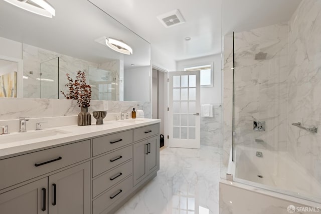 full bathroom with marble tiled flooring, double vanity, and shower / bath combination with glass door