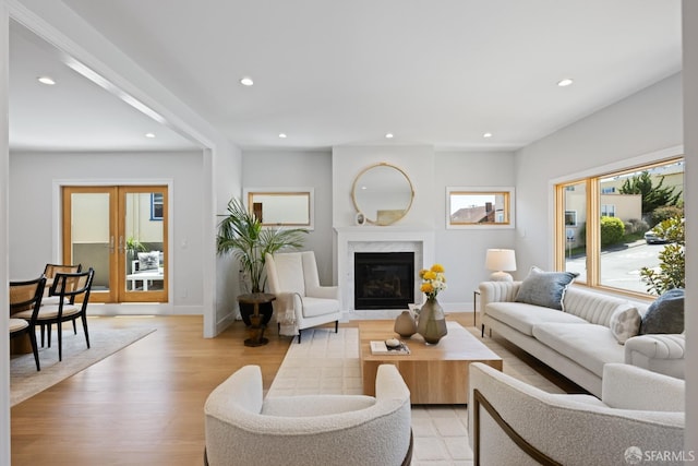 living room featuring recessed lighting, light wood finished floors, baseboards, and a high end fireplace