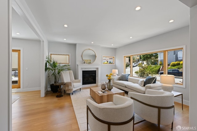 living area with light wood-style floors, recessed lighting, baseboards, and a premium fireplace