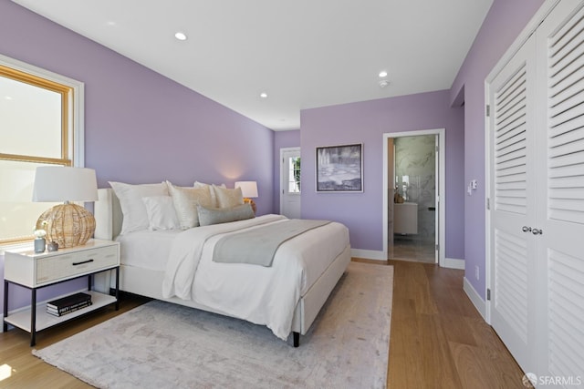 bedroom with wood finished floors, baseboards, recessed lighting, and a closet