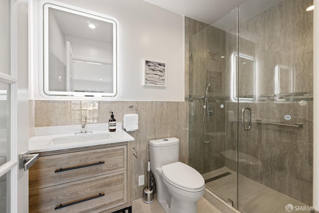 bathroom featuring a stall shower, toilet, vanity, and tile walls