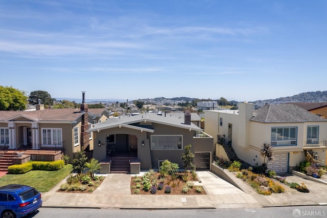 view of front of house with stucco siding, concrete driveway, an attached garage, and a residential view