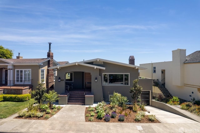 bungalow-style house featuring stucco siding, driveway, a porch, and stairway