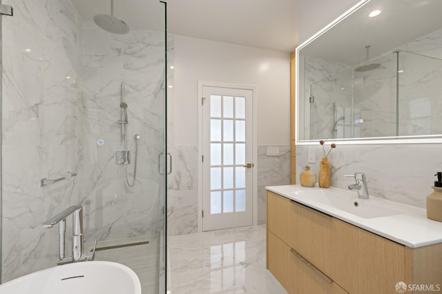 full bath with a marble finish shower, tile walls, marble tiled flooring, a freestanding tub, and vanity