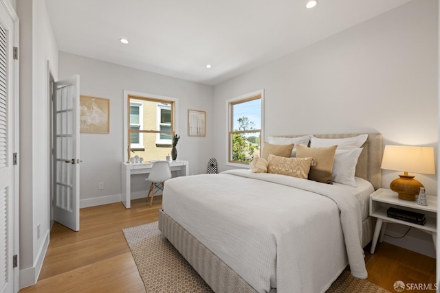 bedroom featuring recessed lighting, light wood-type flooring, baseboards, and an office area