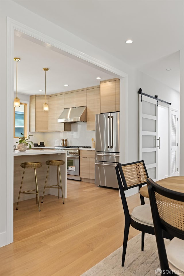 kitchen with high quality appliances, extractor fan, modern cabinets, a breakfast bar area, and recessed lighting