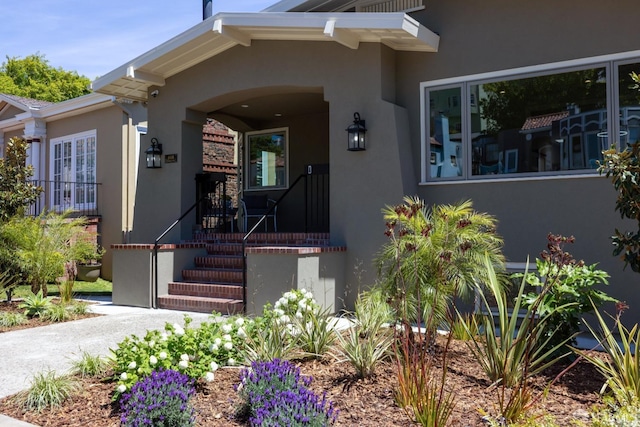 doorway to property with stucco siding and covered porch