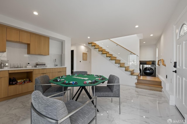 recreation room with light marble finish flooring, recessed lighting, washer and dryer, and a sink