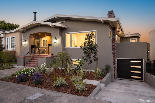 view of front facade featuring stucco siding, driveway, an attached garage, and a chimney