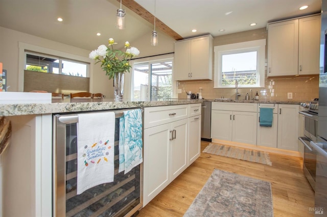 kitchen with wine cooler, a healthy amount of sunlight, light wood-style flooring, and a sink