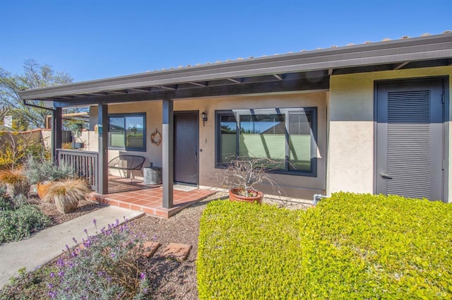 rear view of property with a porch and stucco siding