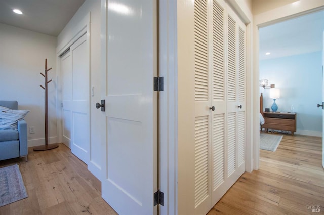 hallway with light wood-style flooring, baseboards, and recessed lighting