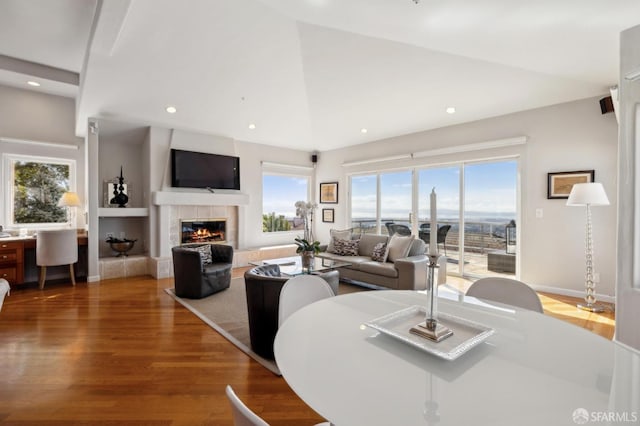 dining space with baseboards, lofted ceiling, wood finished floors, a fireplace, and recessed lighting