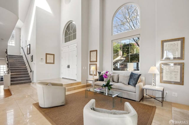 living area featuring light tile patterned floors, stairs, and a high ceiling