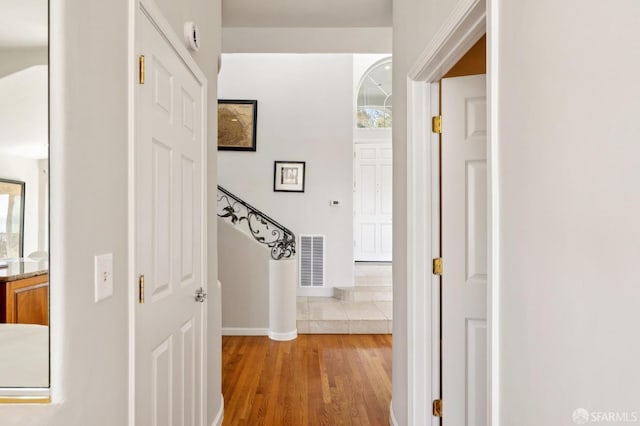 corridor with light wood-style floors, baseboards, and visible vents