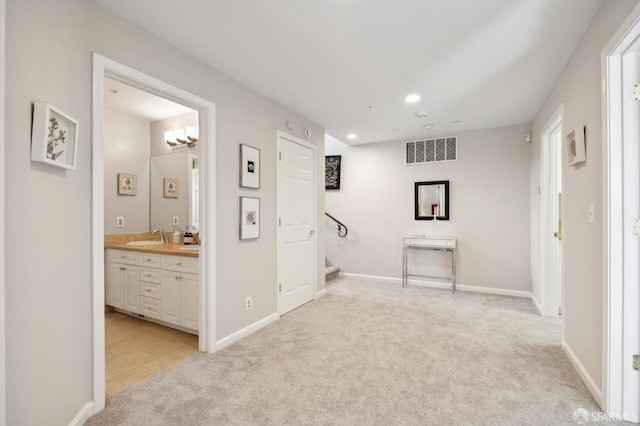 hall featuring recessed lighting, visible vents, light carpet, a sink, and baseboards