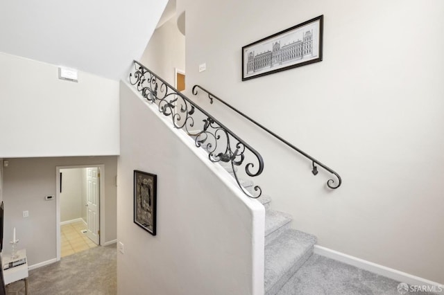 staircase featuring carpet, a towering ceiling, and baseboards