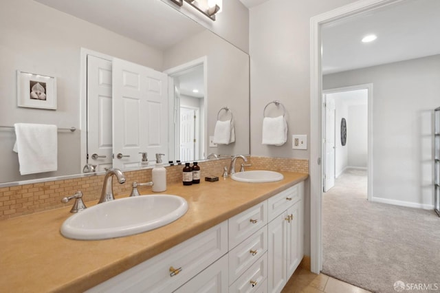 full bath with baseboards, double vanity, a sink, and decorative backsplash