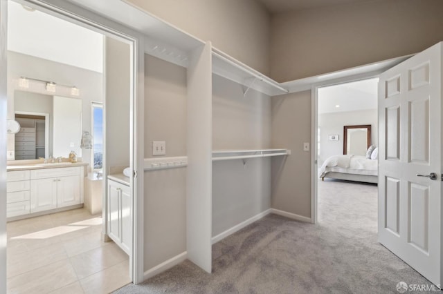 spacious closet featuring light carpet, light tile patterned floors, and a sink