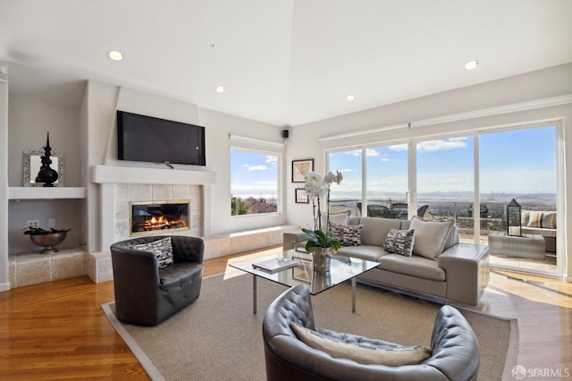 living room featuring recessed lighting, a tiled fireplace, and wood finished floors