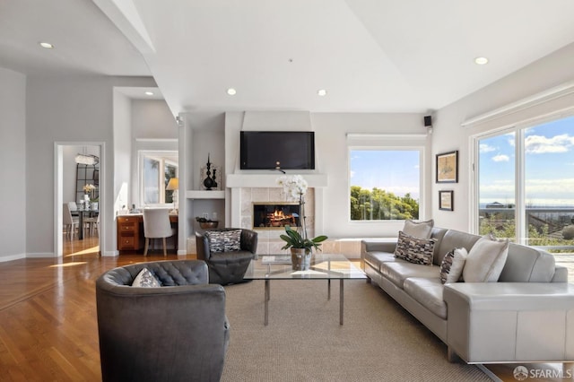 living room featuring baseboards, a tiled fireplace, wood finished floors, and recessed lighting