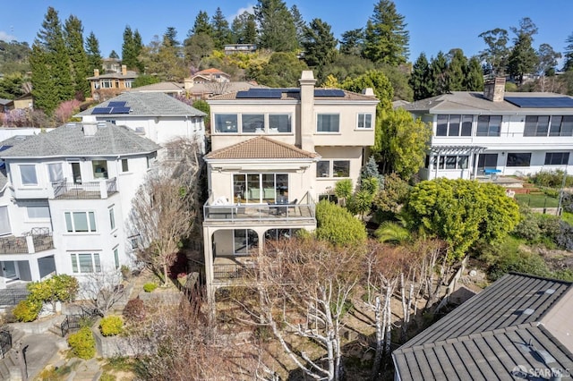 back of property with a balcony, a residential view, a chimney, and stucco siding