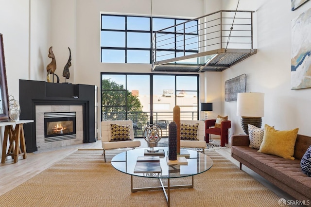 living room featuring hardwood / wood-style flooring, a towering ceiling, and a tile fireplace