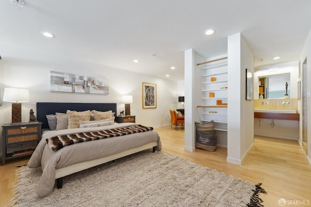 bedroom with ensuite bathroom and light hardwood / wood-style flooring