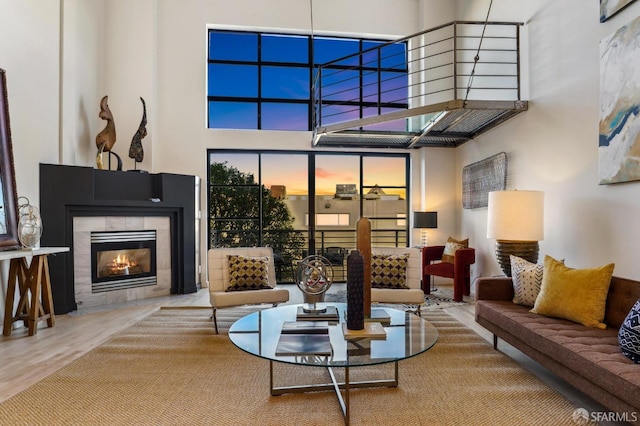 living room featuring a tile fireplace, a high ceiling, and hardwood / wood-style flooring