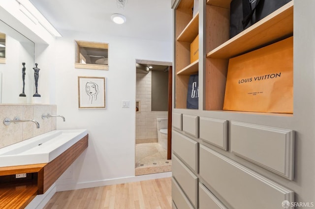 bathroom featuring sink, a shower, toilet, decorative backsplash, and hardwood / wood-style flooring