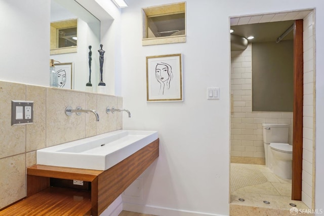 bathroom featuring toilet, tile walls, and sink