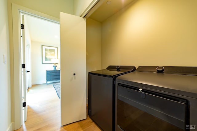 laundry room with separate washer and dryer, laundry area, and light wood-style flooring