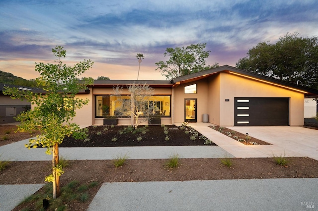 contemporary house with an attached garage, driveway, and stucco siding