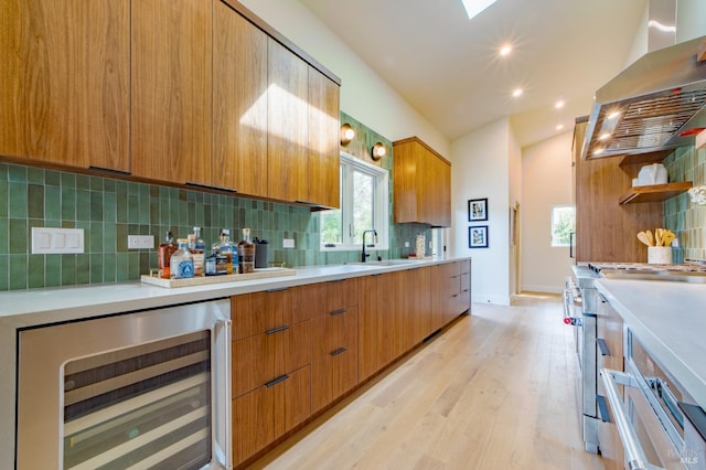 kitchen featuring modern cabinets, stainless steel range, light countertops, island exhaust hood, and beverage cooler