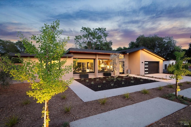 contemporary home featuring a garage, stucco siding, and concrete driveway