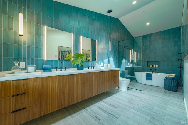 full bathroom with a sink, tile walls, a soaking tub, and lofted ceiling