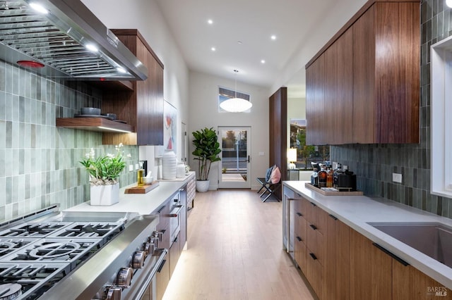 kitchen featuring light wood-style flooring, tasteful backsplash, wall chimney exhaust hood, and modern cabinets