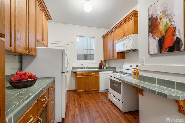 3046-3048 Polk St, San Francisco, CA 94109 - kitchen with white appliances, tile counters, wood finished floors, brown cabinetry, and ornamental molding