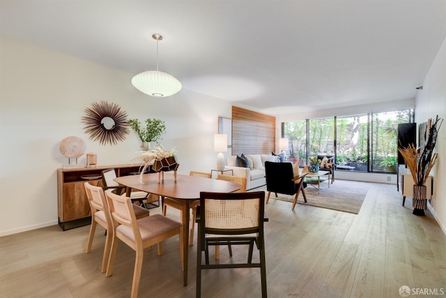 dining area with baseboards, expansive windows, and light wood-style floors